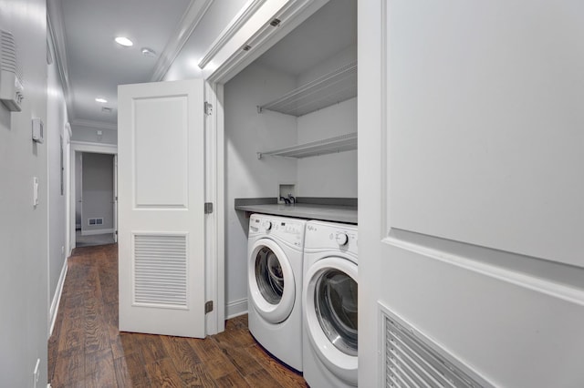 clothes washing area featuring ornamental molding, dark hardwood / wood-style floors, and washing machine and clothes dryer