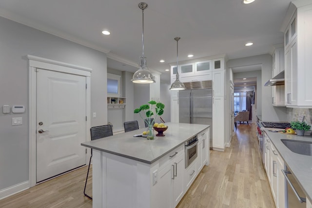 kitchen featuring high end appliances, white cabinetry, a kitchen island, hanging light fixtures, and a breakfast bar area