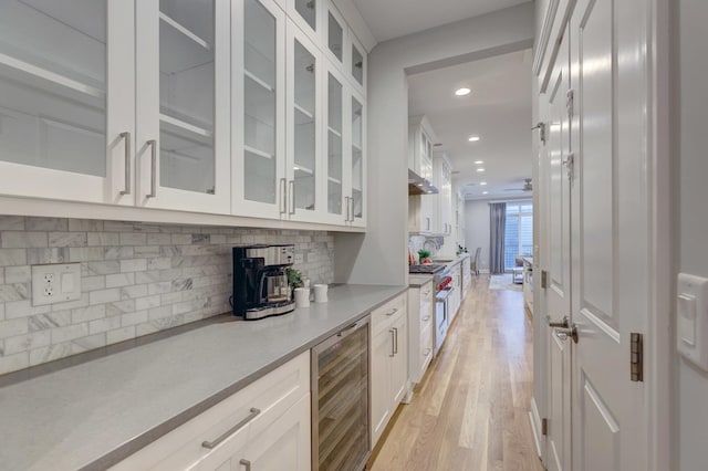 interior space with white cabinetry, tasteful backsplash, wine cooler, and light hardwood / wood-style flooring