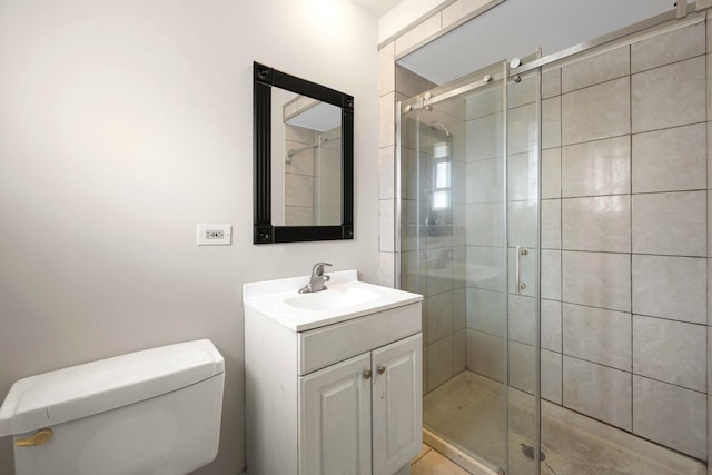 bathroom featuring a shower with door, vanity, and toilet