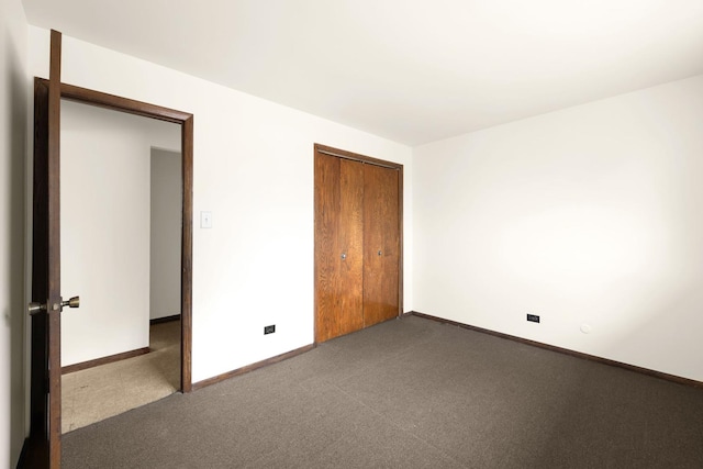 unfurnished bedroom with dark carpet and a closet