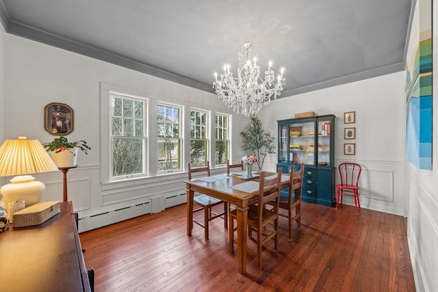 dining space featuring hardwood / wood-style flooring, a baseboard heating unit, a decorative wall, and crown molding