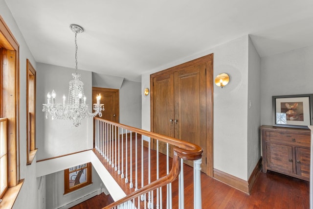 hall with baseboards, a notable chandelier, an upstairs landing, and wood finished floors