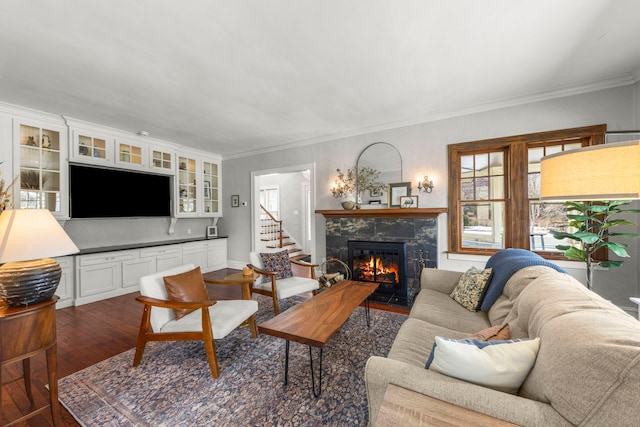 living room featuring a fireplace with flush hearth, ornamental molding, and dark wood finished floors