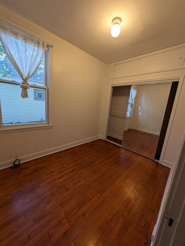 unfurnished bedroom with dark hardwood / wood-style floors and a closet