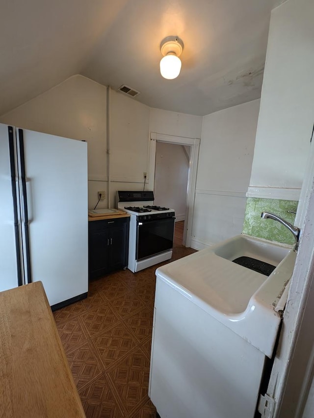 kitchen with white appliances, lofted ceiling, and sink