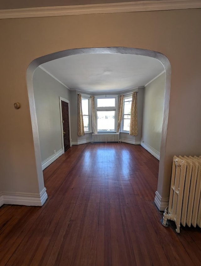 spare room with dark hardwood / wood-style flooring, crown molding, and radiator heating unit