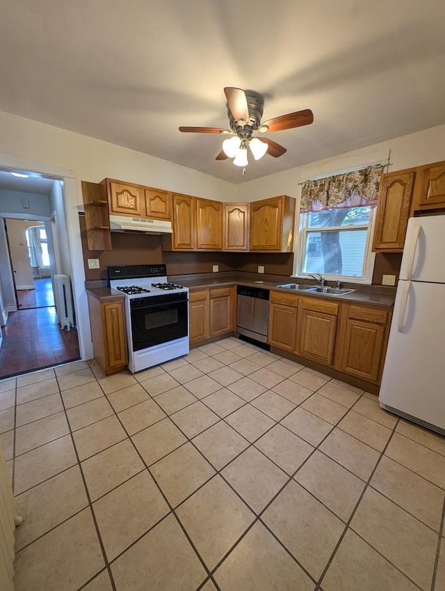 kitchen with radiator heating unit, range with gas stovetop, dishwasher, sink, and white fridge