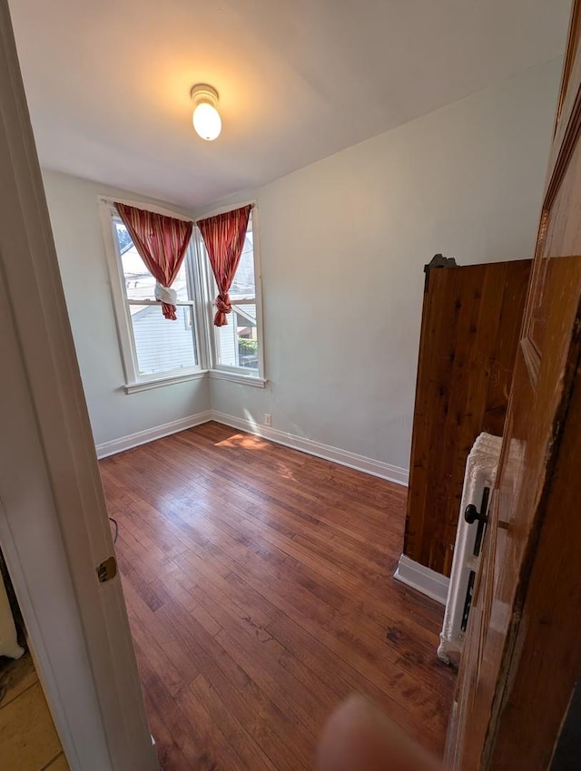 spare room featuring radiator heating unit and dark hardwood / wood-style flooring