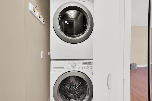 clothes washing area with stacked washer / drying machine and hardwood / wood-style flooring