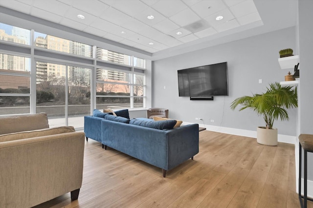 living room with a drop ceiling and light wood-type flooring