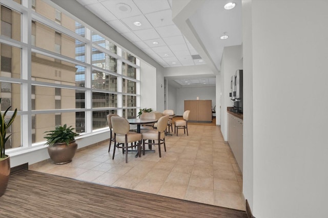 dining room with a healthy amount of sunlight, a paneled ceiling, and light tile patterned floors