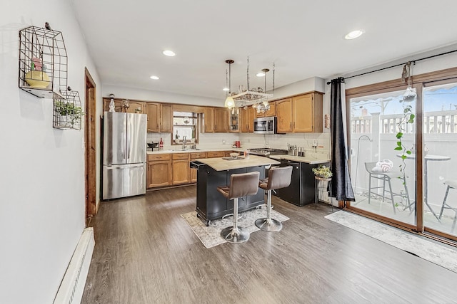 kitchen with appliances with stainless steel finishes, a kitchen breakfast bar, dark hardwood / wood-style flooring, hanging light fixtures, and a center island