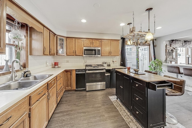 kitchen featuring dark hardwood / wood-style floors, pendant lighting, sink, backsplash, and stainless steel appliances