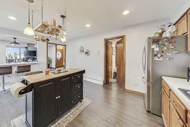 kitchen with stainless steel refrigerator, decorative light fixtures, dark hardwood / wood-style flooring, a baseboard heating unit, and a center island