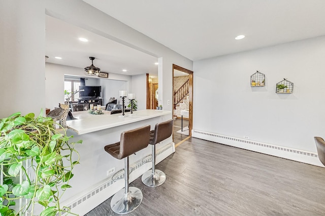 kitchen featuring a kitchen breakfast bar, dark hardwood / wood-style flooring, baseboard heating, and kitchen peninsula