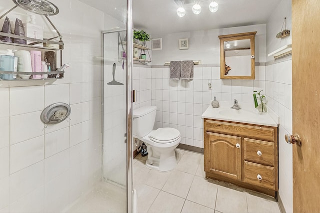 bathroom featuring tile walls, vanity, toilet, a shower with door, and tile patterned floors