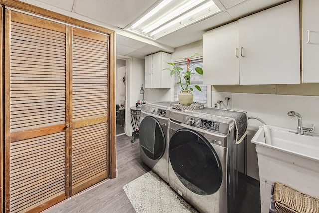 clothes washing area with cabinets, independent washer and dryer, and light hardwood / wood-style floors