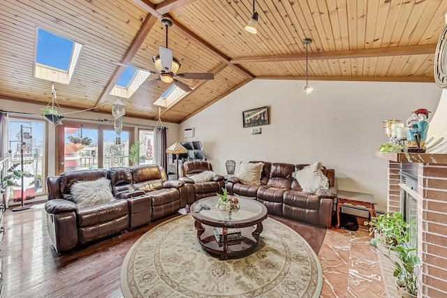 living room with lofted ceiling with skylight, a fireplace, wood-type flooring, ceiling fan, and wooden ceiling