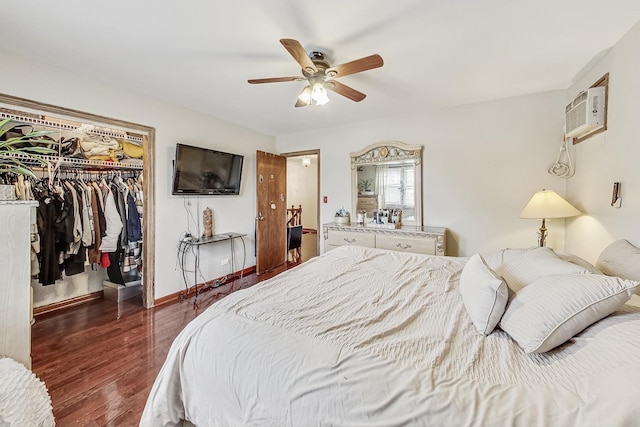 bedroom with an AC wall unit, a walk in closet, ceiling fan, dark wood-type flooring, and a closet