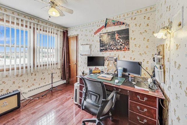 home office featuring baseboard heating, ceiling fan, and hardwood / wood-style floors