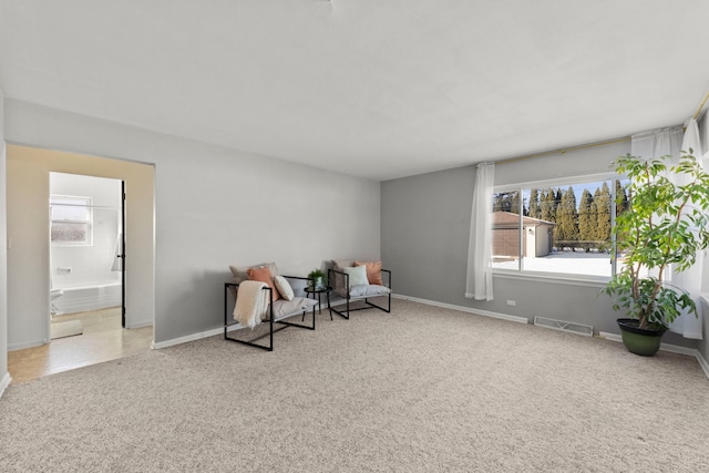 sitting room with light colored carpet, visible vents, and baseboards