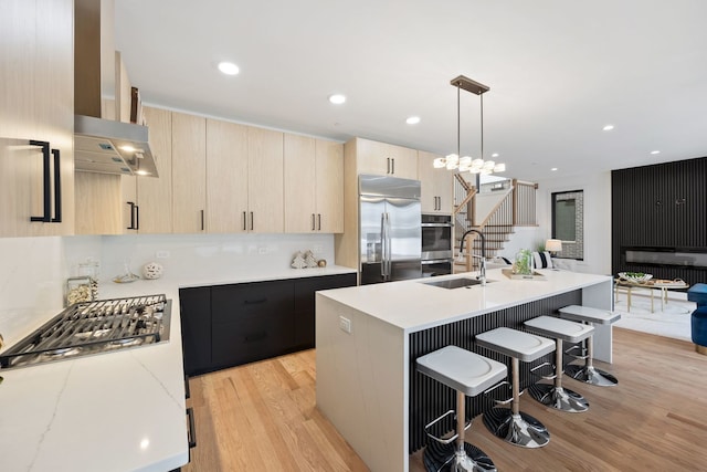 kitchen with a sink, appliances with stainless steel finishes, light brown cabinetry, light wood finished floors, and modern cabinets