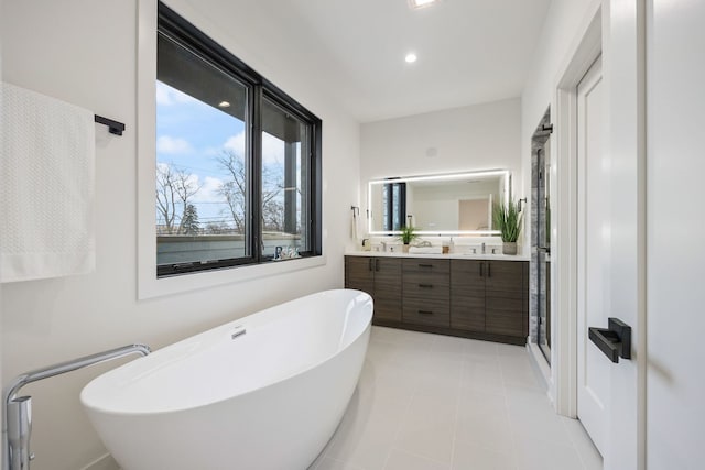 full bathroom featuring double vanity, a freestanding bath, and recessed lighting