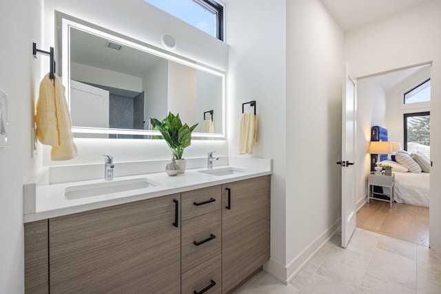 ensuite bathroom with visible vents, a sink, baseboards, and ensuite bathroom