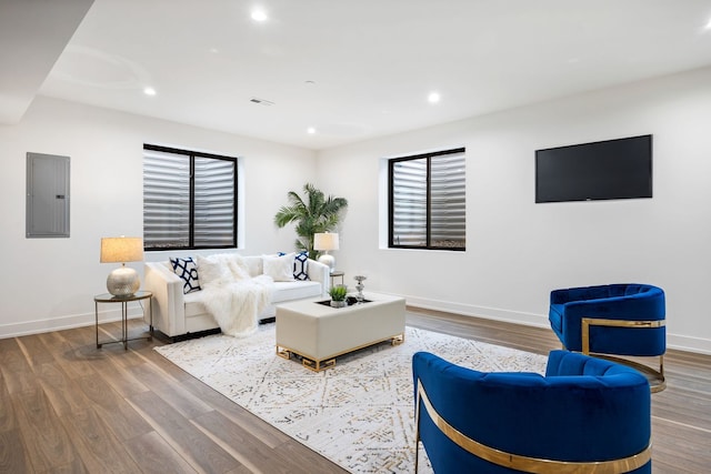 living area with electric panel, baseboards, wood finished floors, and recessed lighting