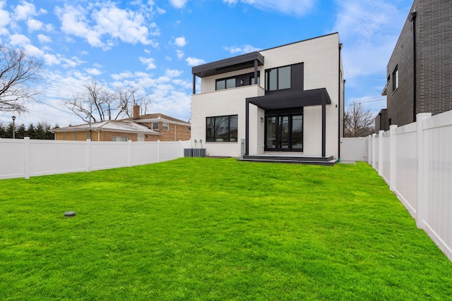 back of house with a fenced backyard, a lawn, a balcony, and stucco siding