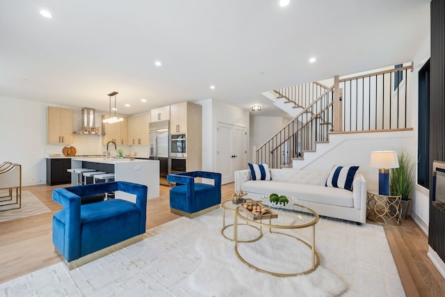 living area with light wood-type flooring, stairway, and recessed lighting