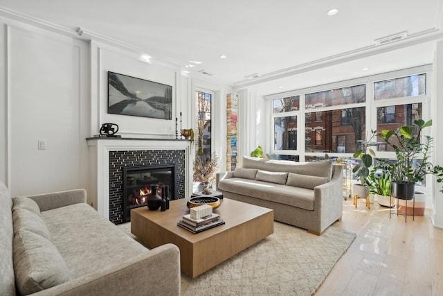 living area with a tile fireplace, visible vents, light wood-style flooring, and recessed lighting