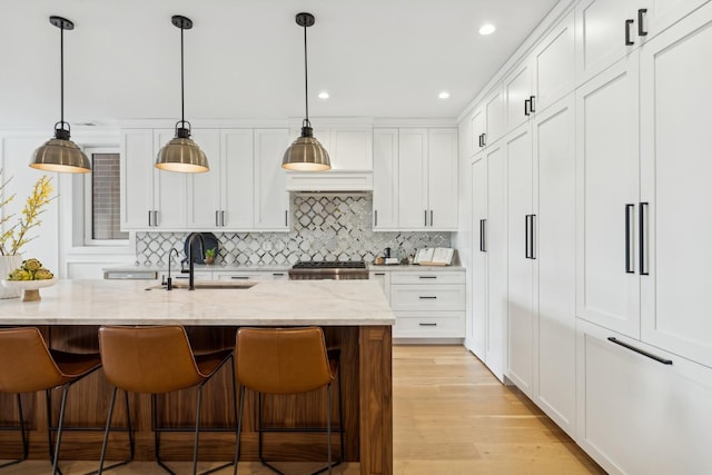 kitchen featuring light stone counters, a sink, white cabinetry, range, and pendant lighting