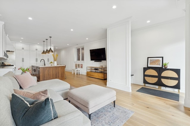 living area with ornamental molding, recessed lighting, light wood-style flooring, and baseboards