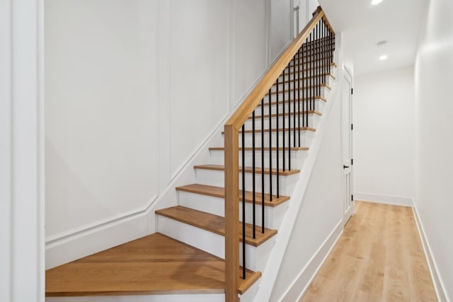 stairway featuring baseboards, wood finished floors, and recessed lighting