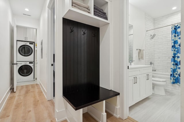 mudroom featuring stacked washing maching and dryer, light wood-style flooring, visible vents, and recessed lighting