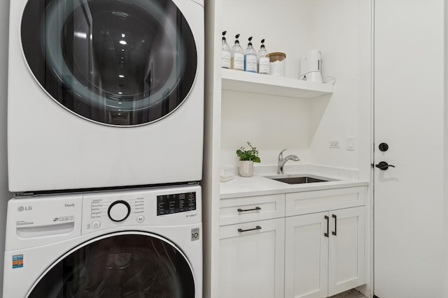 laundry area featuring a sink, cabinet space, and stacked washer / drying machine