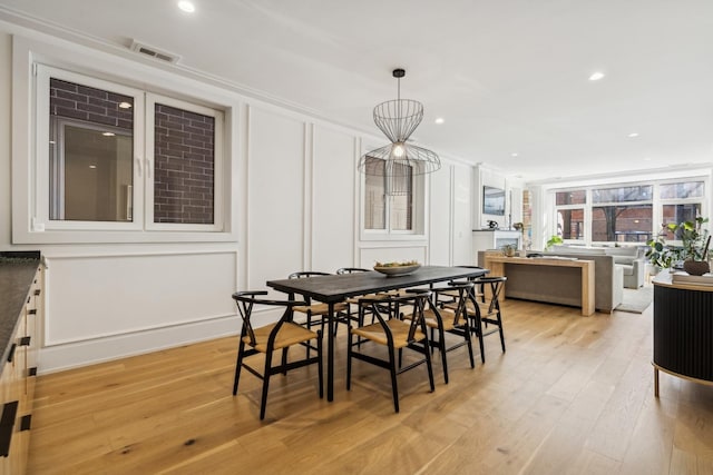 dining area with light wood-style floors, visible vents, a decorative wall, and recessed lighting