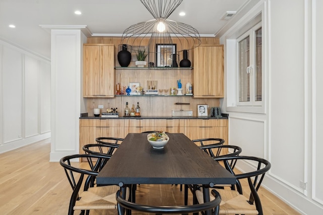 interior space featuring light wood-style floors, ornamental molding, and a decorative wall