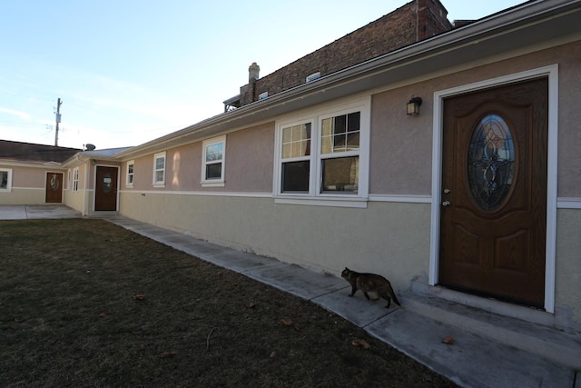 property entrance with a yard and stucco siding