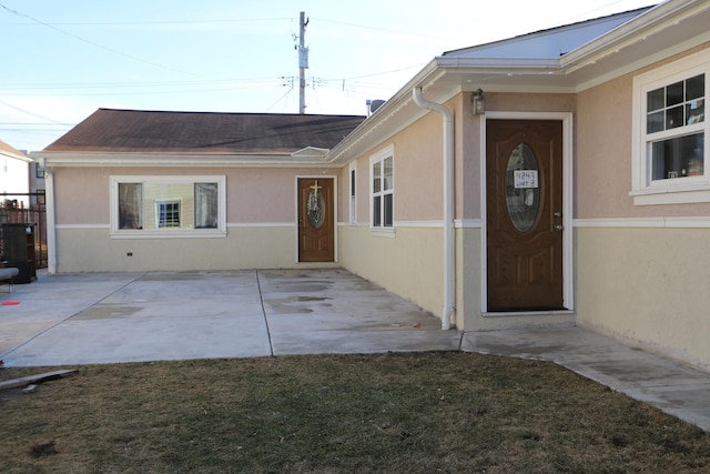 doorway to property featuring stucco siding and a patio