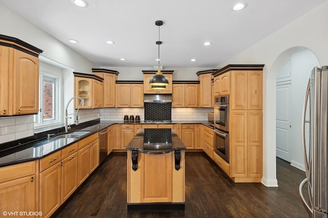 kitchen featuring dark wood-style floors, decorative light fixtures, stainless steel appliances, a kitchen island, and a sink