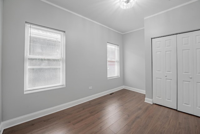 unfurnished bedroom featuring crown molding, dark wood-type flooring, and a closet