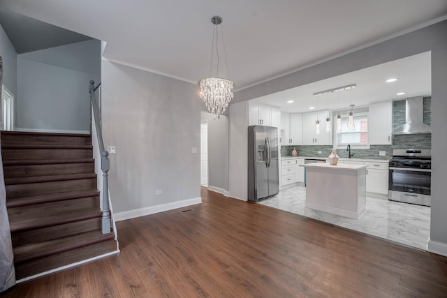 kitchen featuring wall chimney exhaust hood, white cabinetry, stainless steel appliances, and a kitchen island