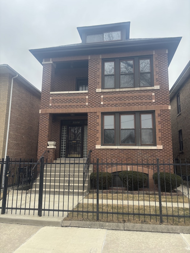 american foursquare style home featuring brick siding and a fenced front yard