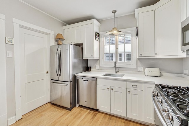 kitchen featuring white cabinets, stainless steel appliances, light countertops, light wood-style floors, and a sink