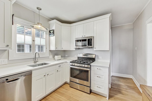 kitchen with stainless steel appliances, crown molding, a sink, and white cabinetry