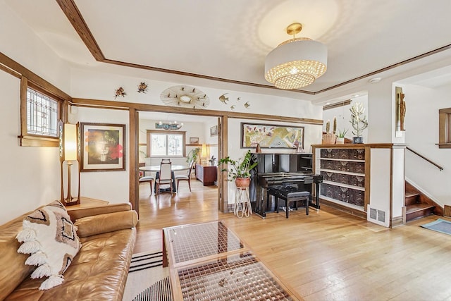 living room featuring a chandelier, wood-type flooring, visible vents, and stairs