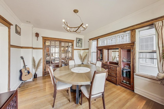 dining area featuring light wood-style flooring, a chandelier, and ornamental molding